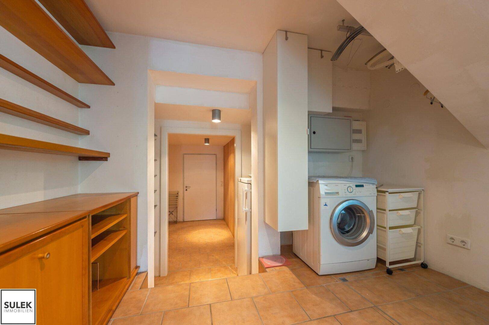 Praktischer Hauswirtschaftsraum mit Waschmaschine, Trockner und Stauraum unter der Treppe.
