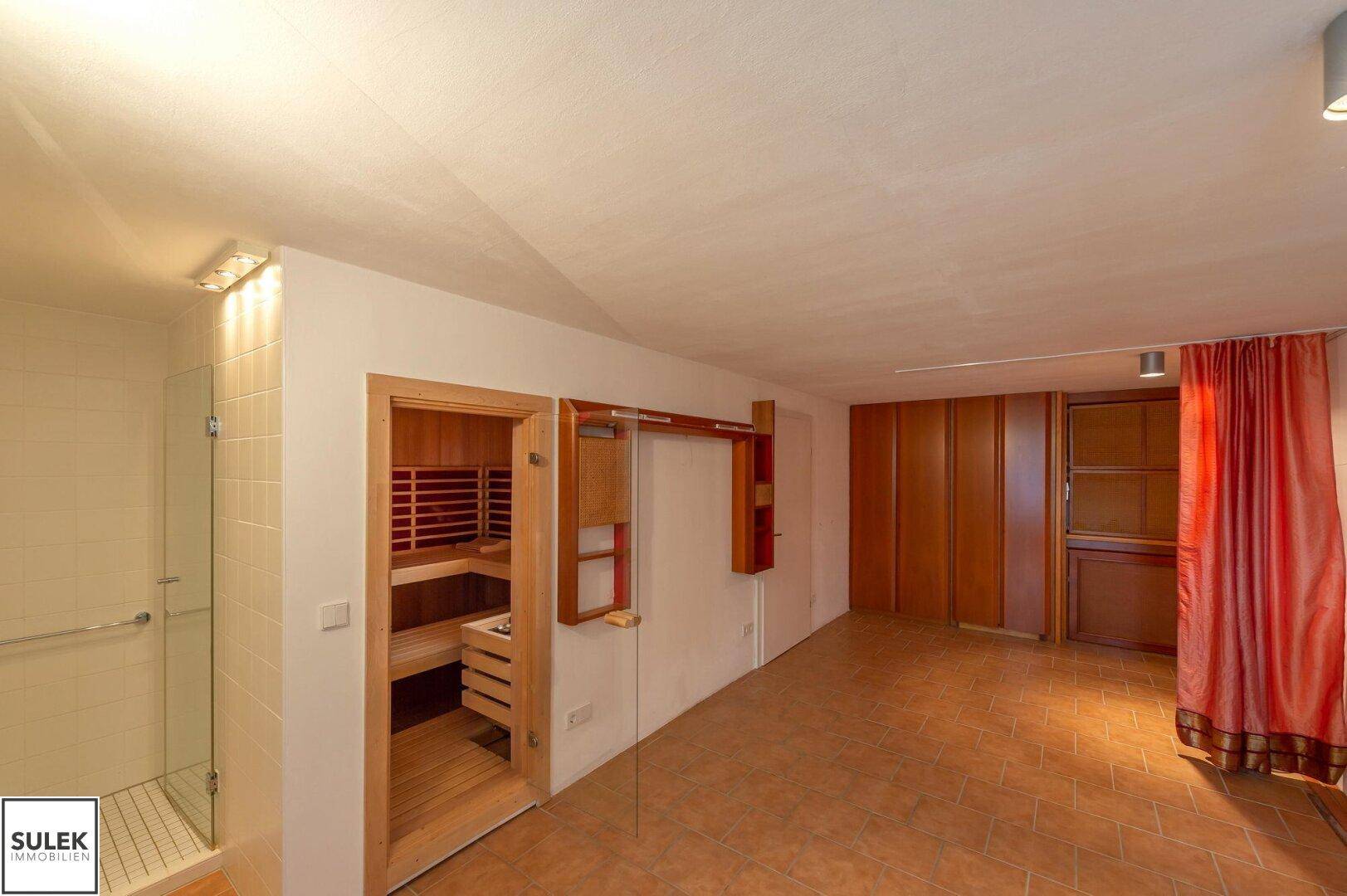 Mehrzweckraum mit Zugang zur Sauna, Einbauschränken und Terrakotta-Fliesenboden, vielseitig nutzbar.