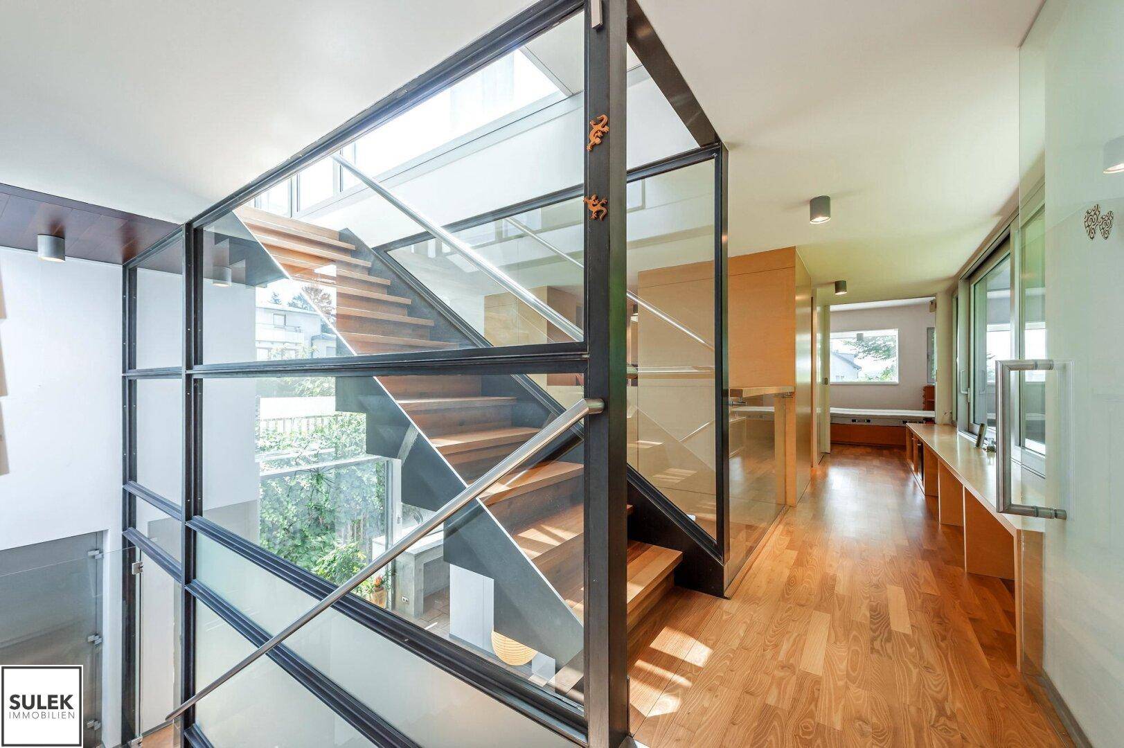 Moderne Treppe mit Glasgeländer und Holzstufen, die verschiedene Ebenen stilvoll miteinander verbindet.