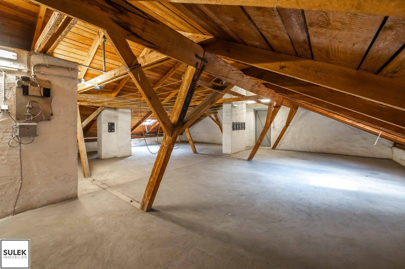 Großer Dachboden mit freiliegenden Holzbalken und Betonboden, bereit für den Ausbau.