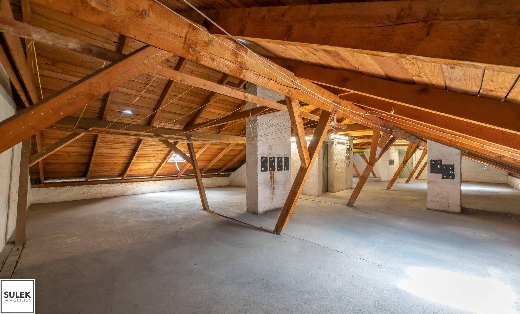 Weitläufiger Dachboden mit robusten Holzbalken und Betonboden, bietet viel Potenzial.