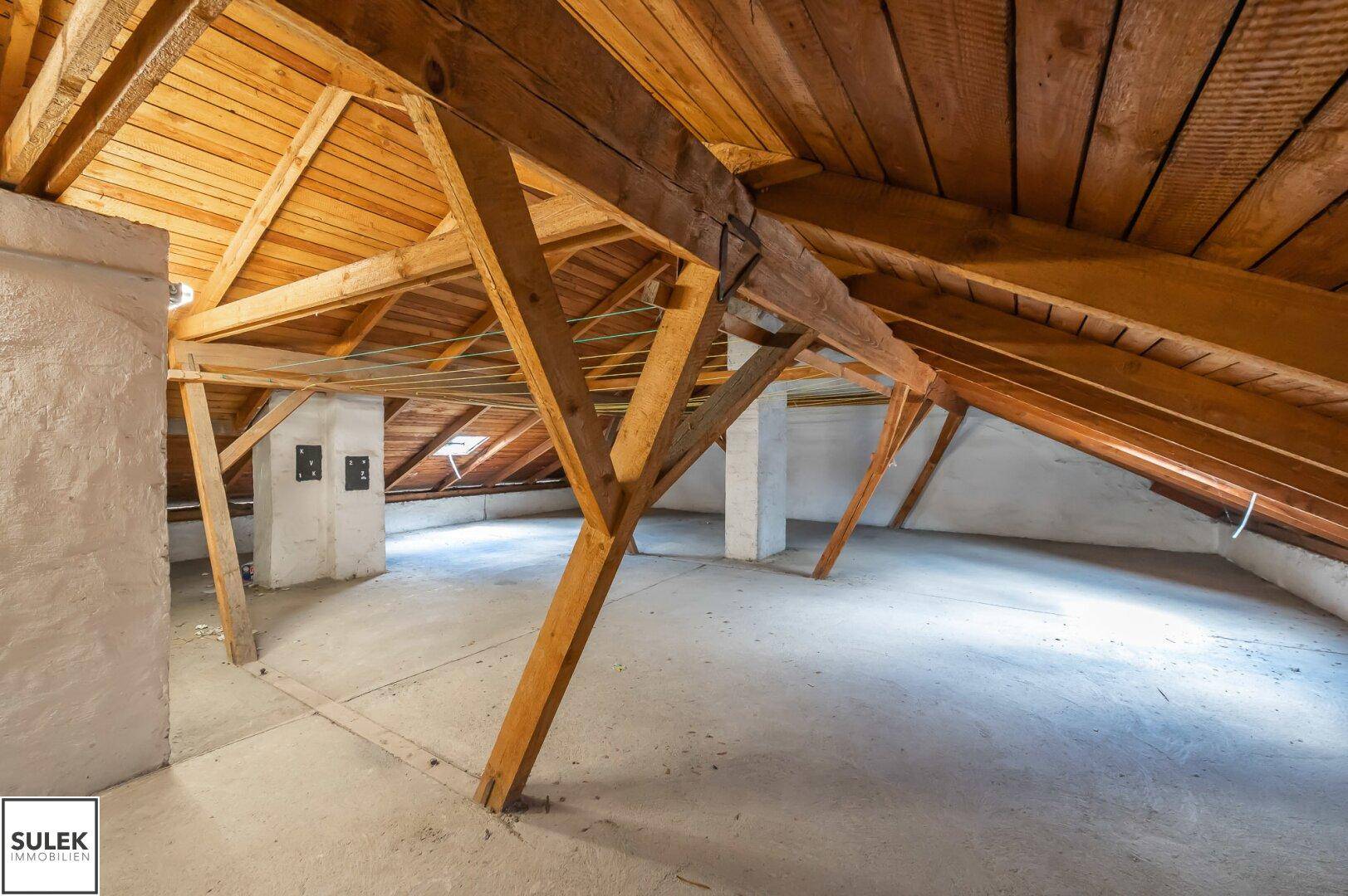 Geräumiger Dachbodenbereich mit sichtbaren Holzkonstruktionen und schrägen Decken.