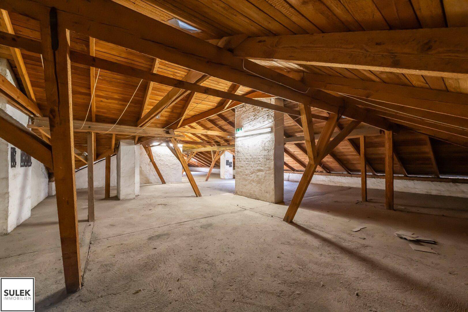 Weitläufiger Dachboden mit robusten Holzbalken und Betonboden, bietet viel Potenzial.