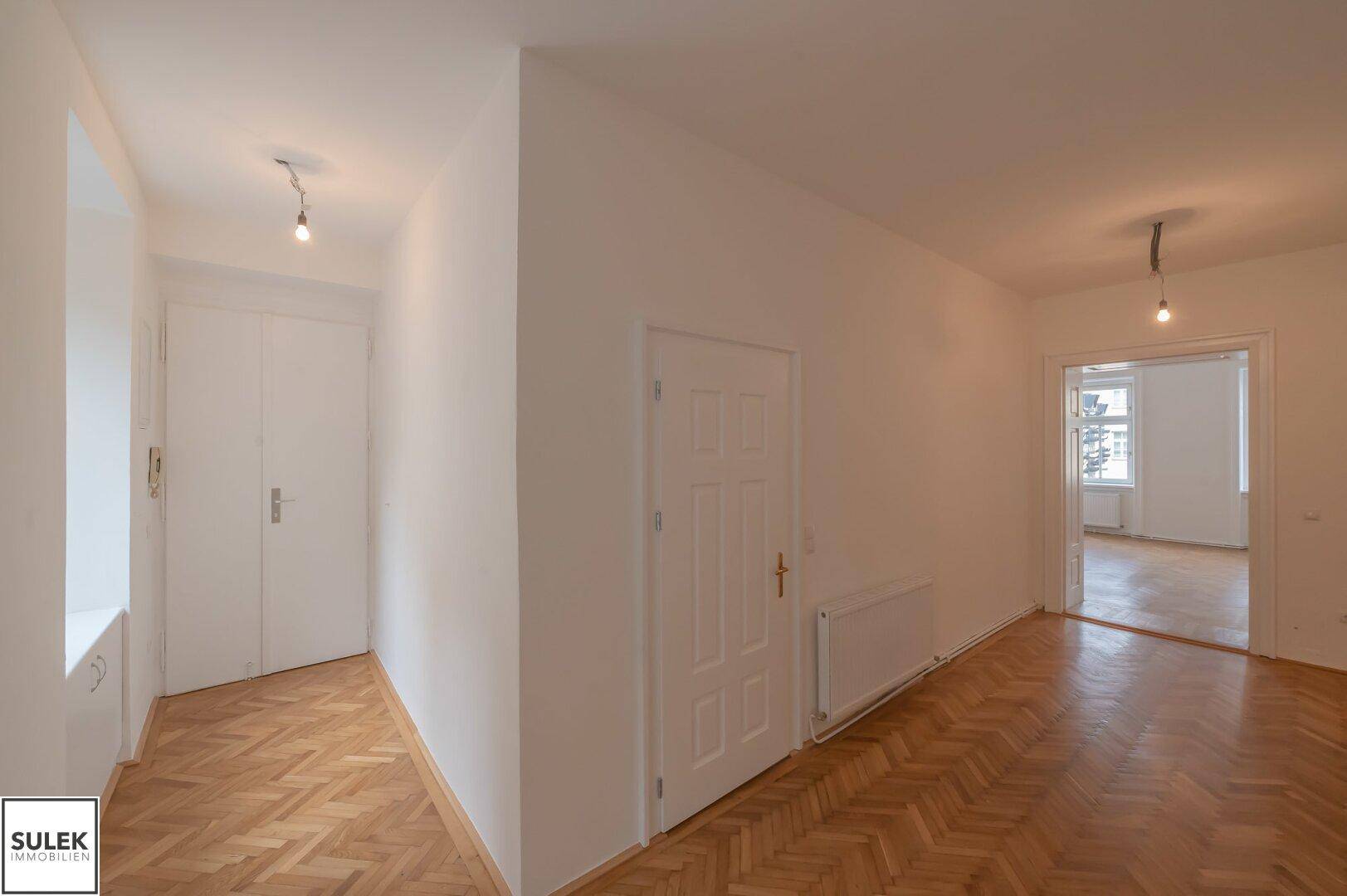 Heller Flur mit Fischgrätparkett und Zugang zu verschiedenen Zimmern der Wohnung.