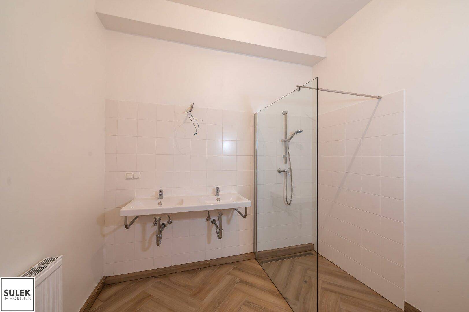 Geräumiges Badezimmer mit zwei Waschbecken und einer modernen, begehbaren Dusche.