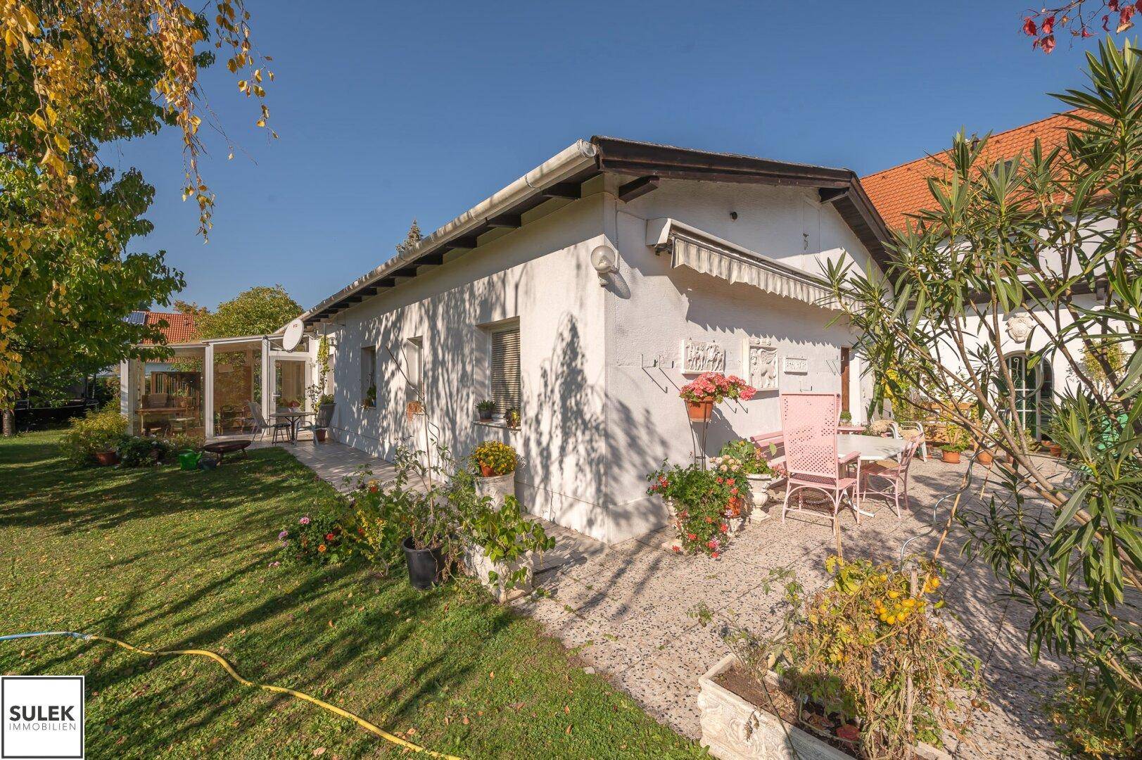 Gemütliche Steinterrasse am Haus mit Gartenmöbeln und Blumen, ideal für entspannte Stunden im Freien.