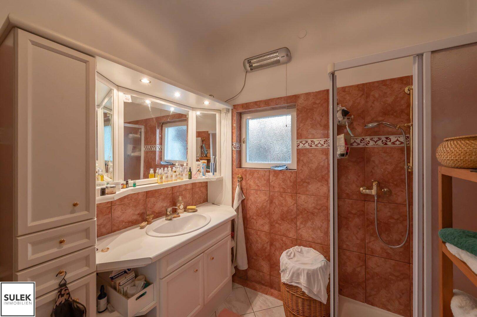 Funktionales Badezimmer mit roten Fliesen, Spiegelschrank und Duschkabine.