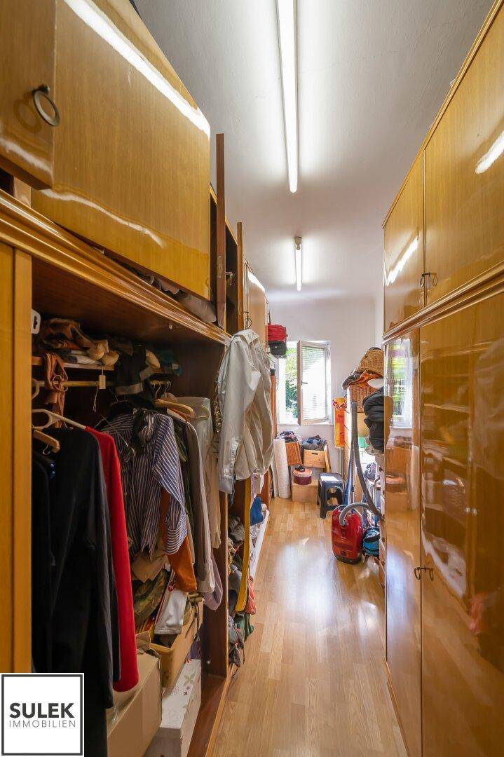 Geräumige Garderobe mit vielen Holzschränken und Regalen für Kleidung und Fenster.