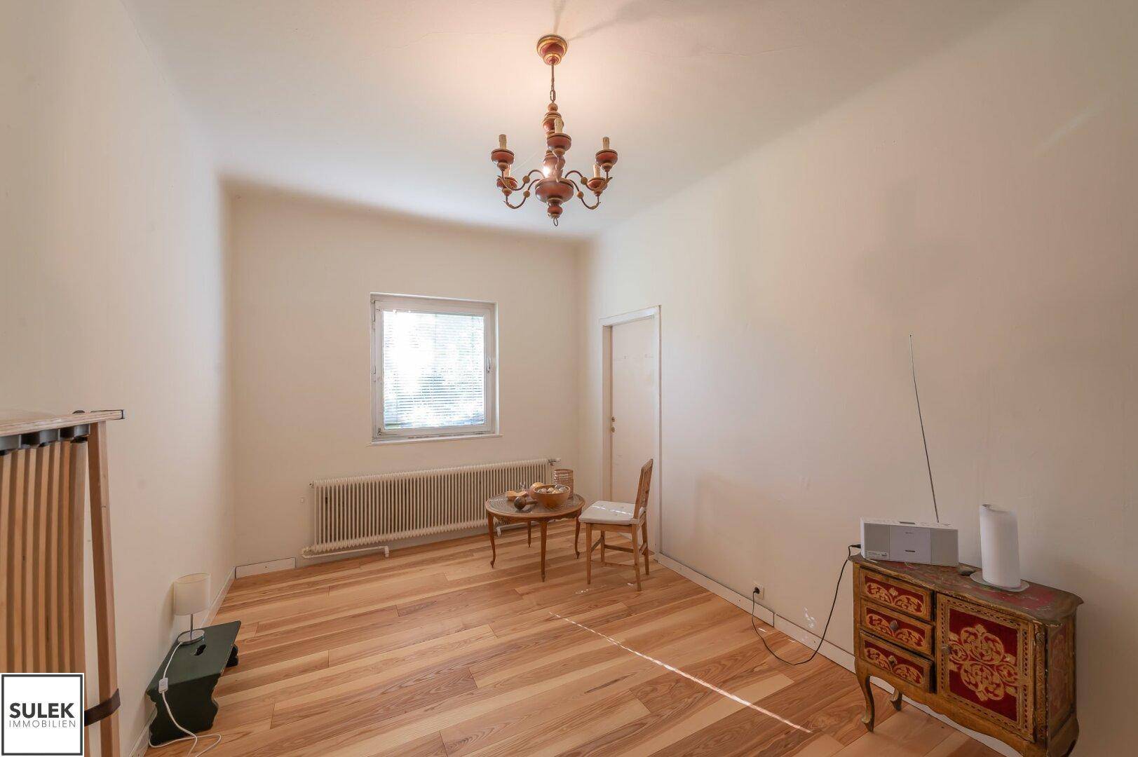 Helles Zimmer mit Parkettboden und klassischem Kronleuchter, vielseitig nutzbar.