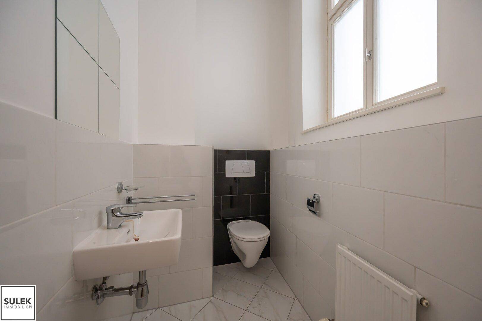 Modernes Gäste-WC mit Fenster, Wand-WC und kleinem Waschbecken.
