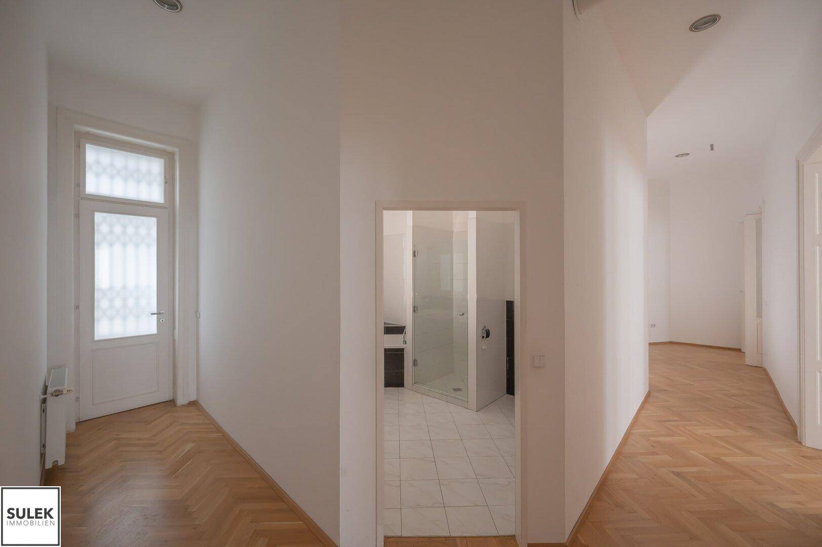 Flur mit Fischgrätparkett und direktem Zugang zu einem Badezimmer.