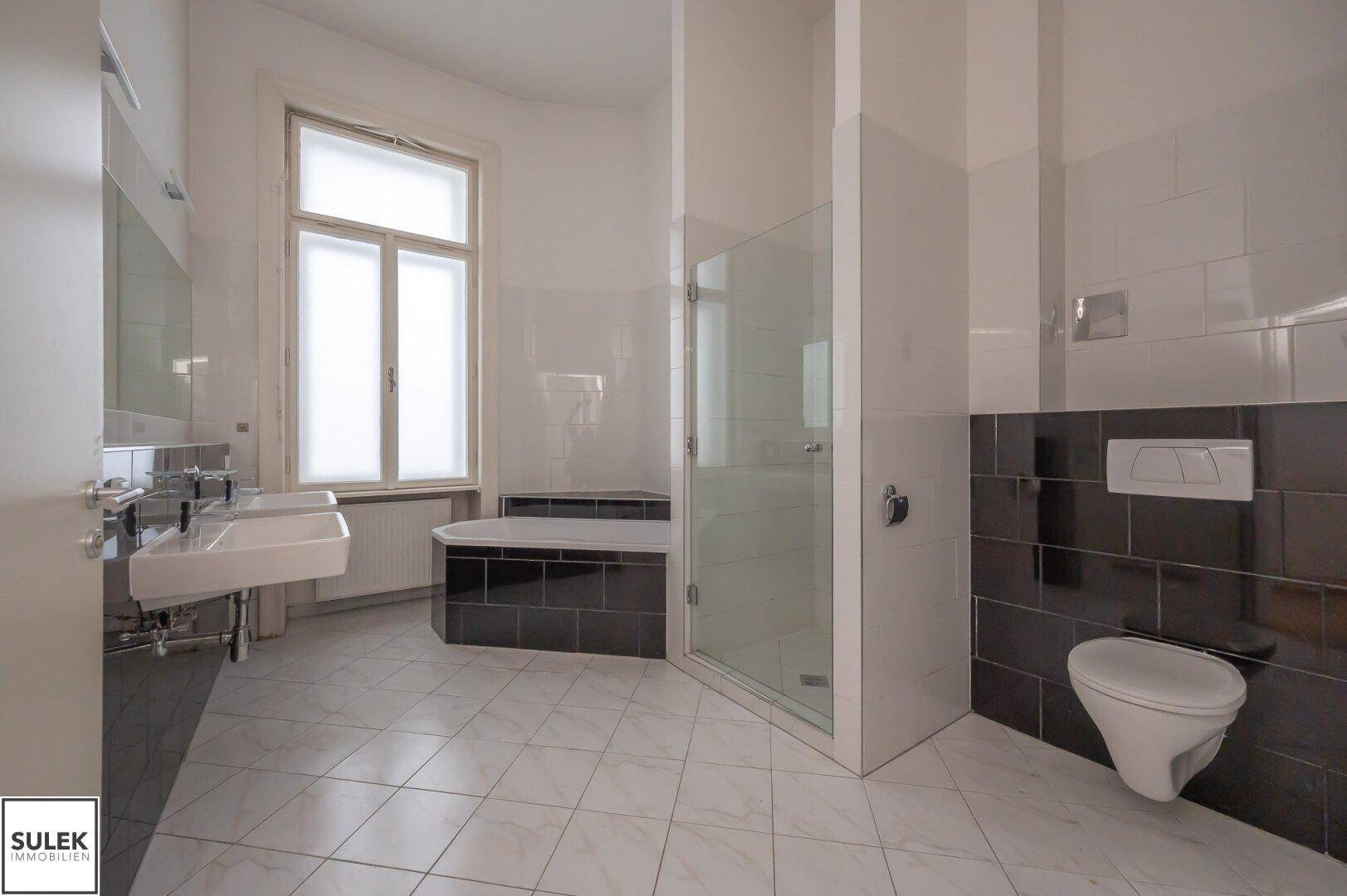 Geräumiges Badezimmer mit Dusche, Badewanne, Wand-WC und Doppelwaschbecken.