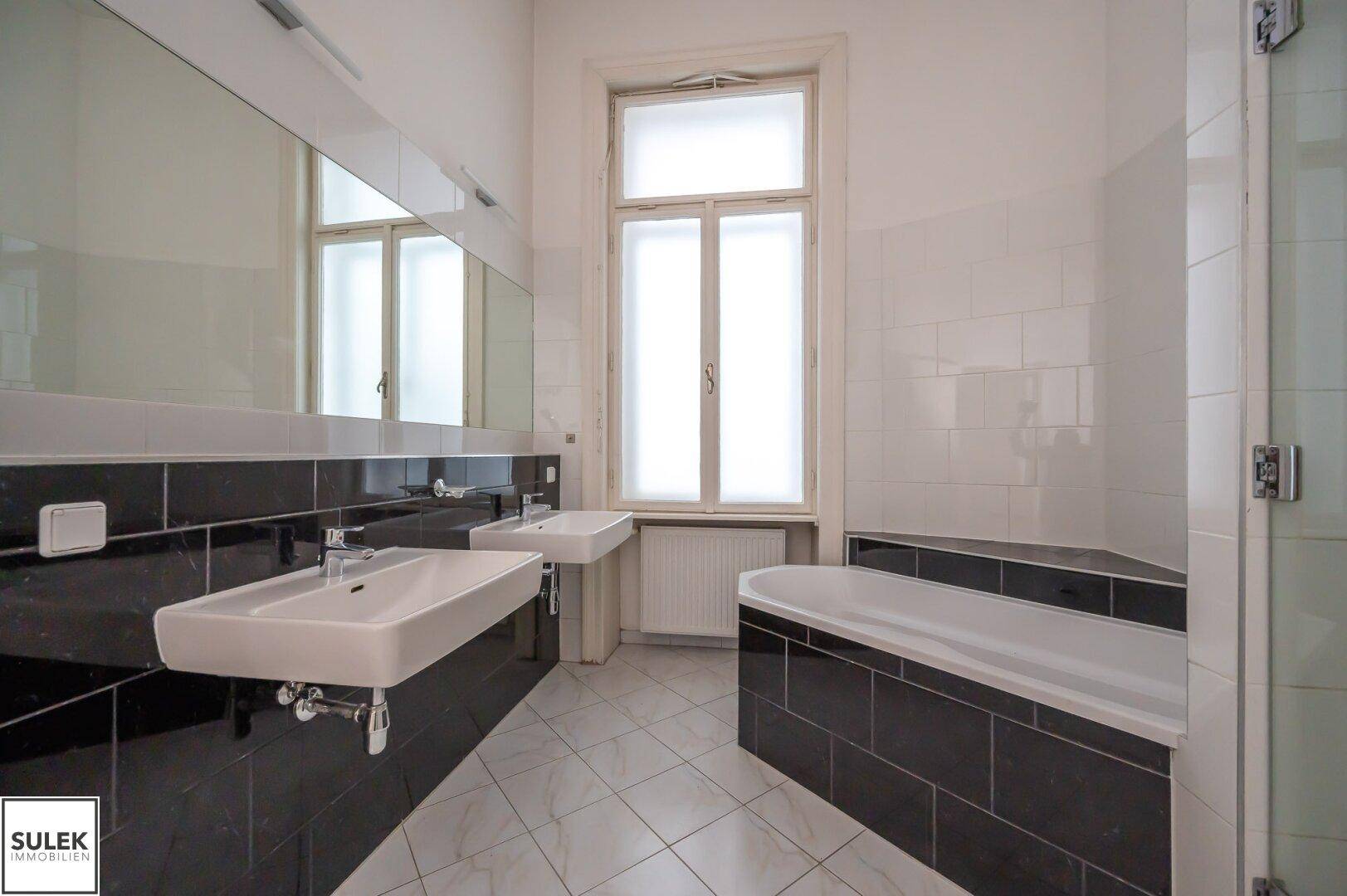 Modernes Badezimmer mit Doppelwaschbecken, Badewanne, Dusche und Fenster.