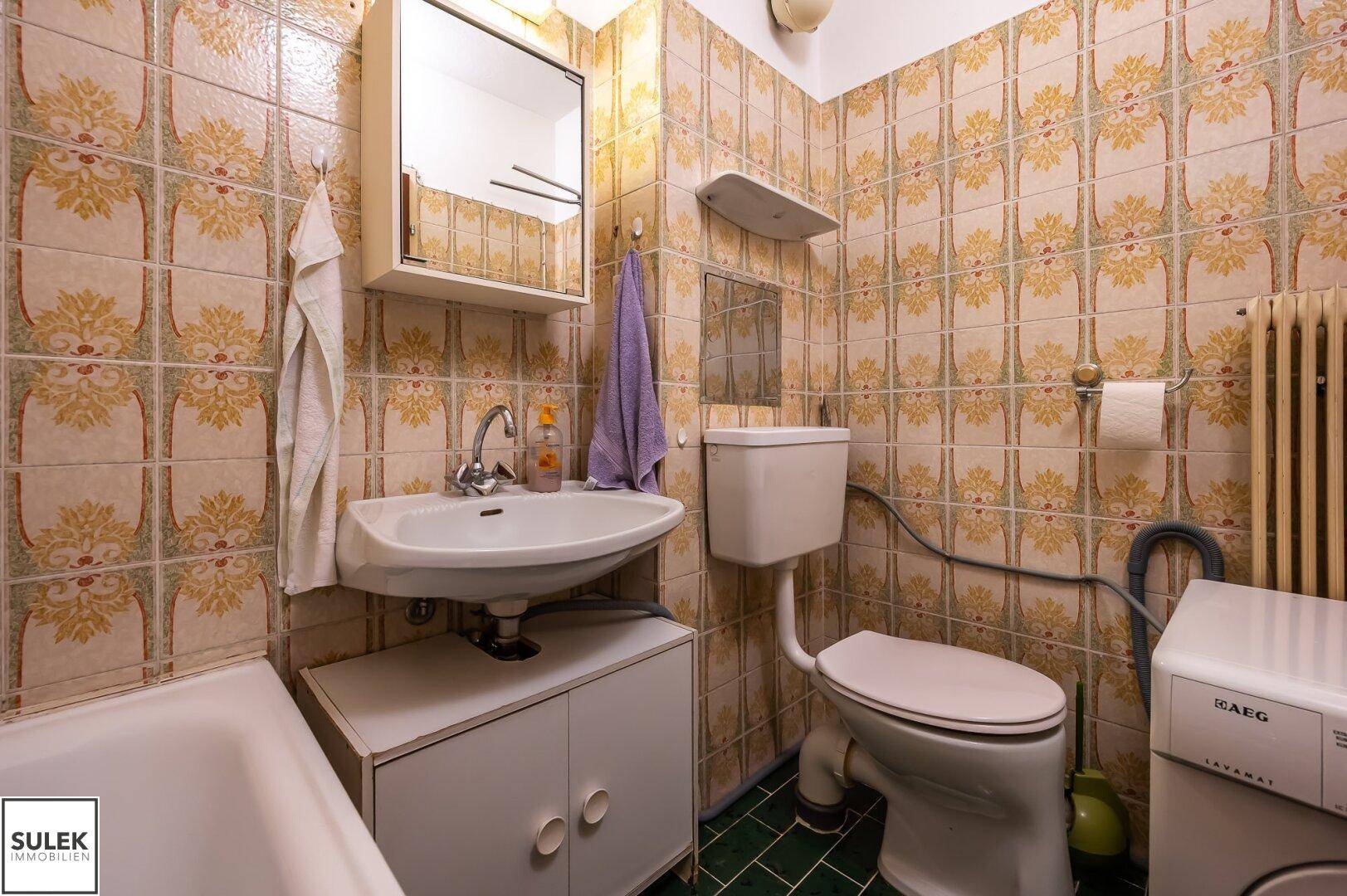 Badezimmer mit WC, Waschbecken und Platz für eine Waschmaschine.