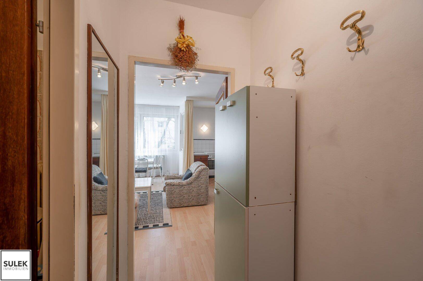 Flur mit Spiegel und Garderobe, der zum hellen Wohnbereich führt.