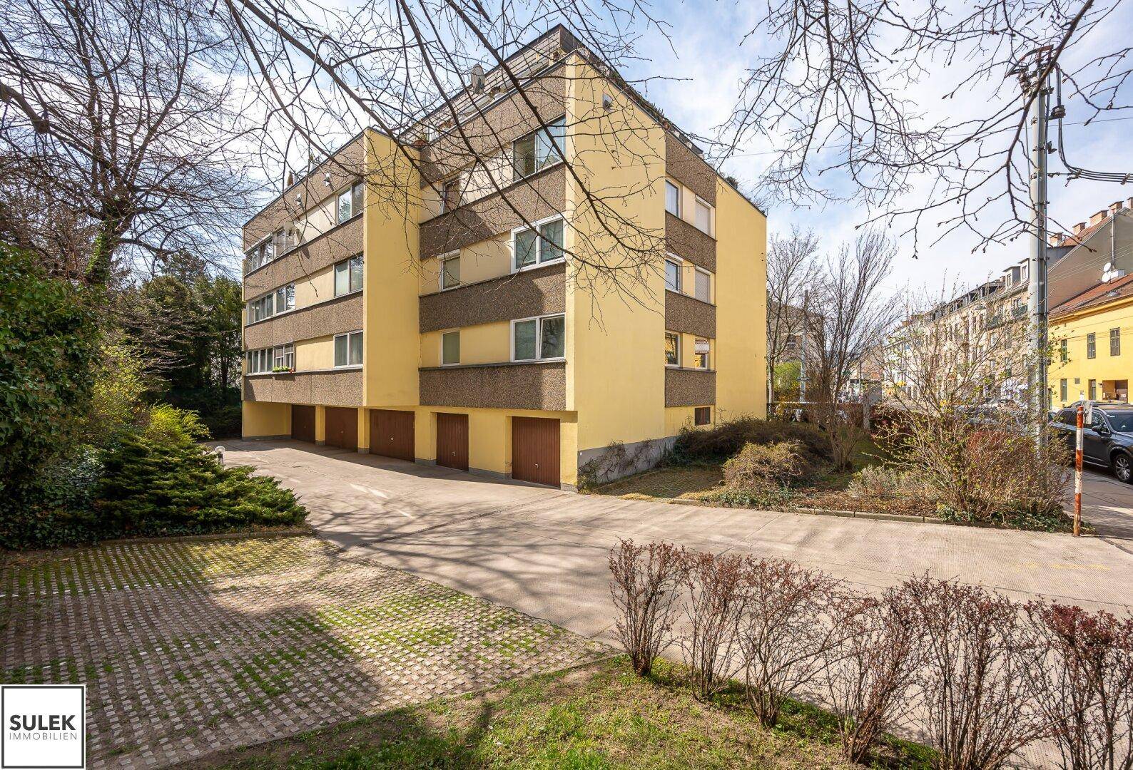 Rückansicht des Gebäudes mit Garagen und Außenparkplätzen.