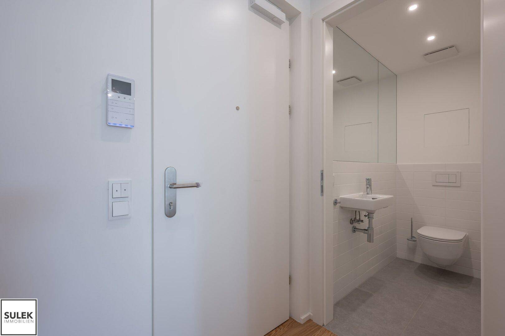 Eingangsbereich mit Gegensprechanlage und Blick in ein modernes Gäste-WC.