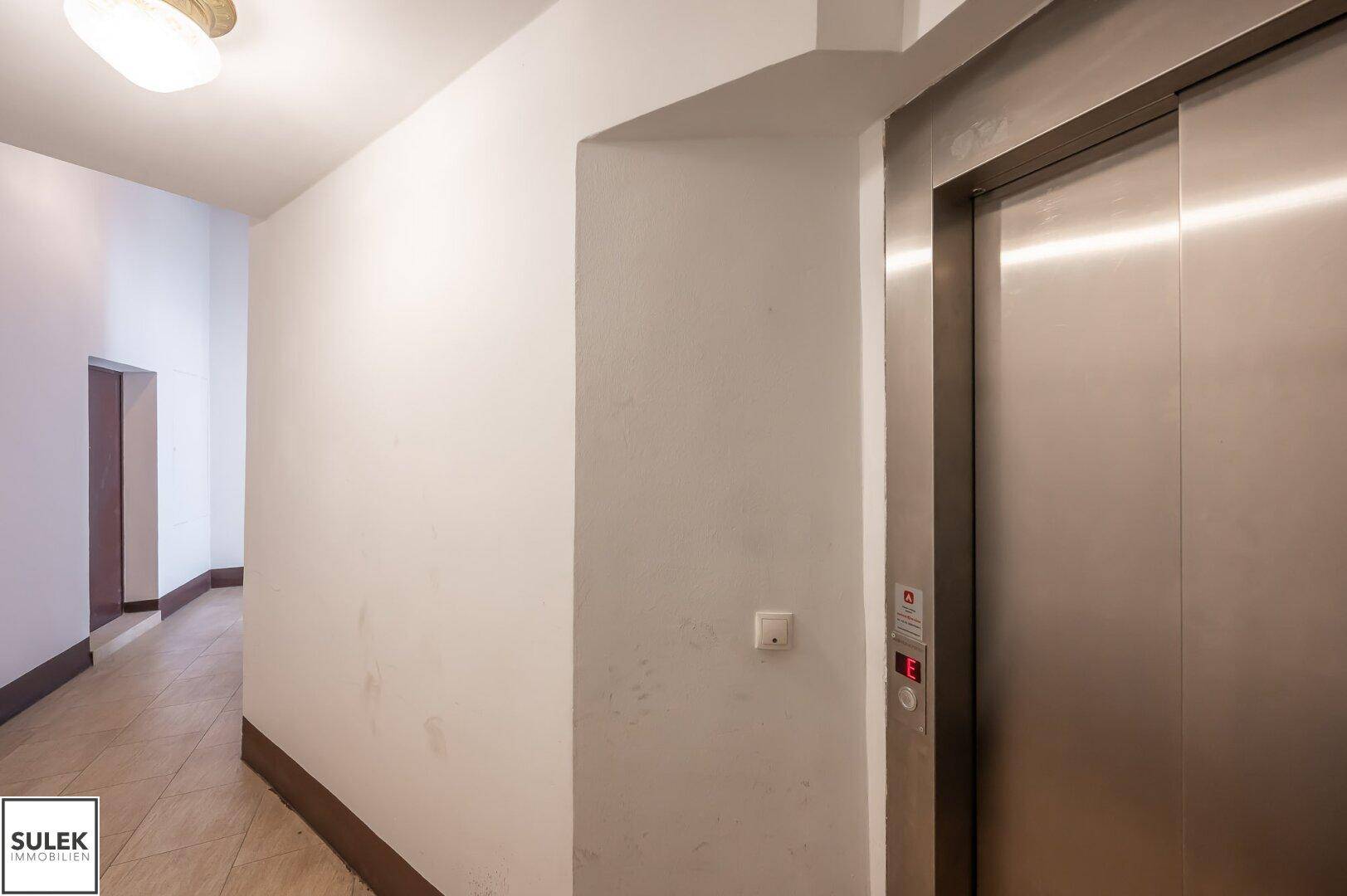 Heller Flur mit Aufzug und schlichtem Design in einem Mehrfamilienhaus.