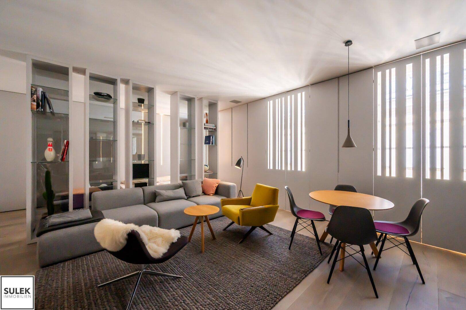 Moderner Wohn- und Essbereich mit stilvollen Möbeln, Holzboden und eleganten Fensterverkleidungen.