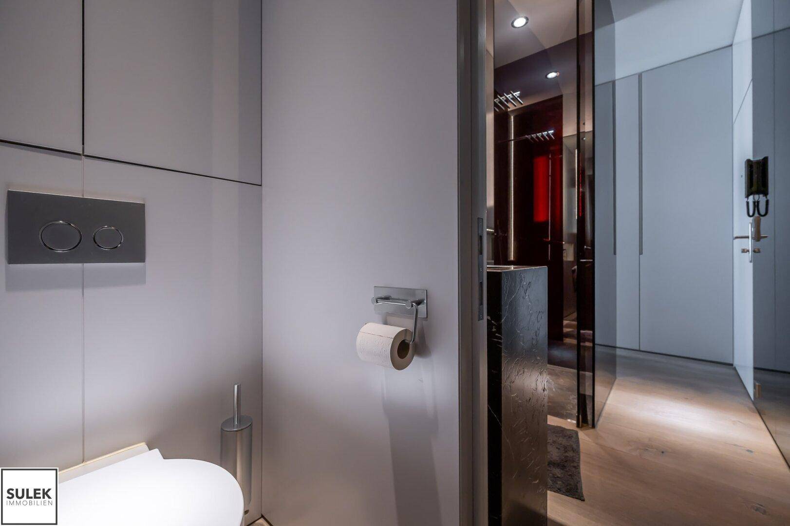 Separate Toilette mit Wand-WC und minimalistischem Design, angrenzend an den Badezimmerbereich.