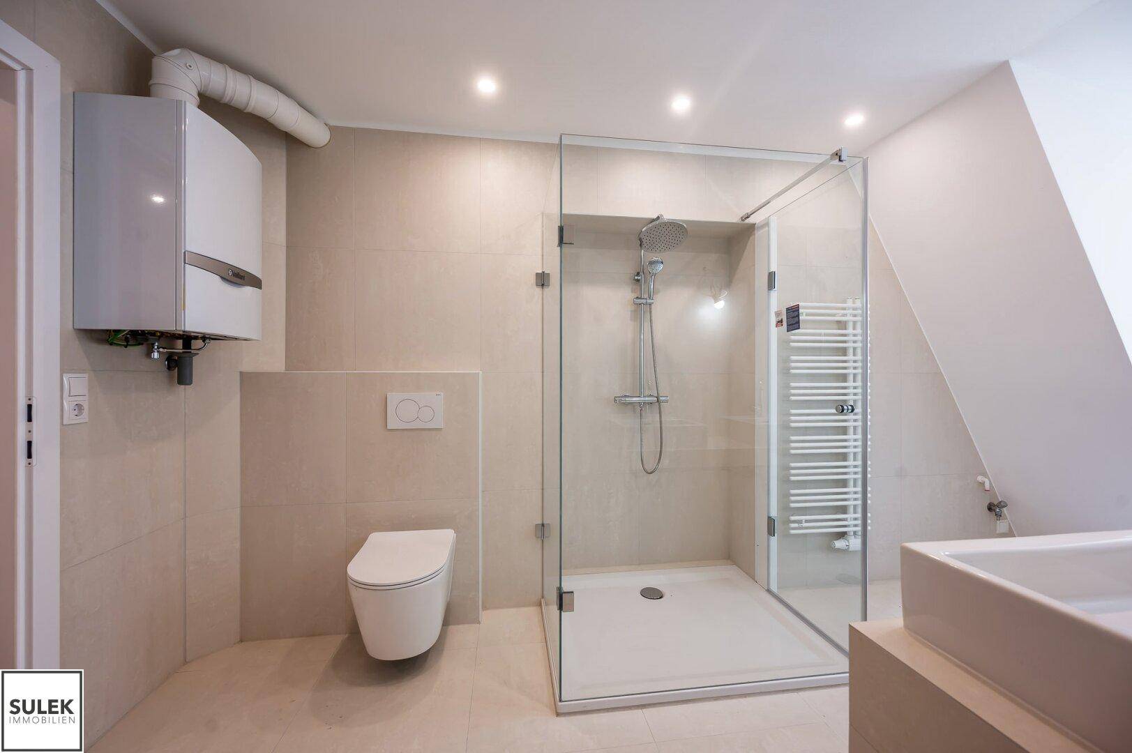 Modernes Badezimmer mit begehbarer Dusche, Wand-WC und Heizkörper, in hellen Farbtönen gehalten.