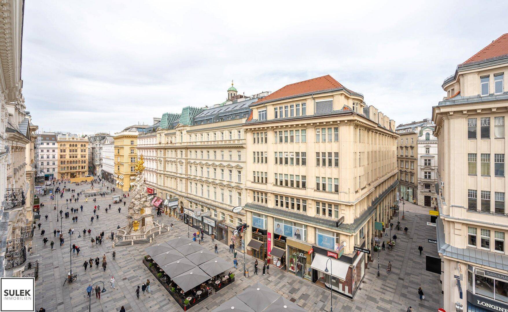Weitläufiger Blick über eine belebte Stadtstraße mit historischen Gebäuden und Geschäften.