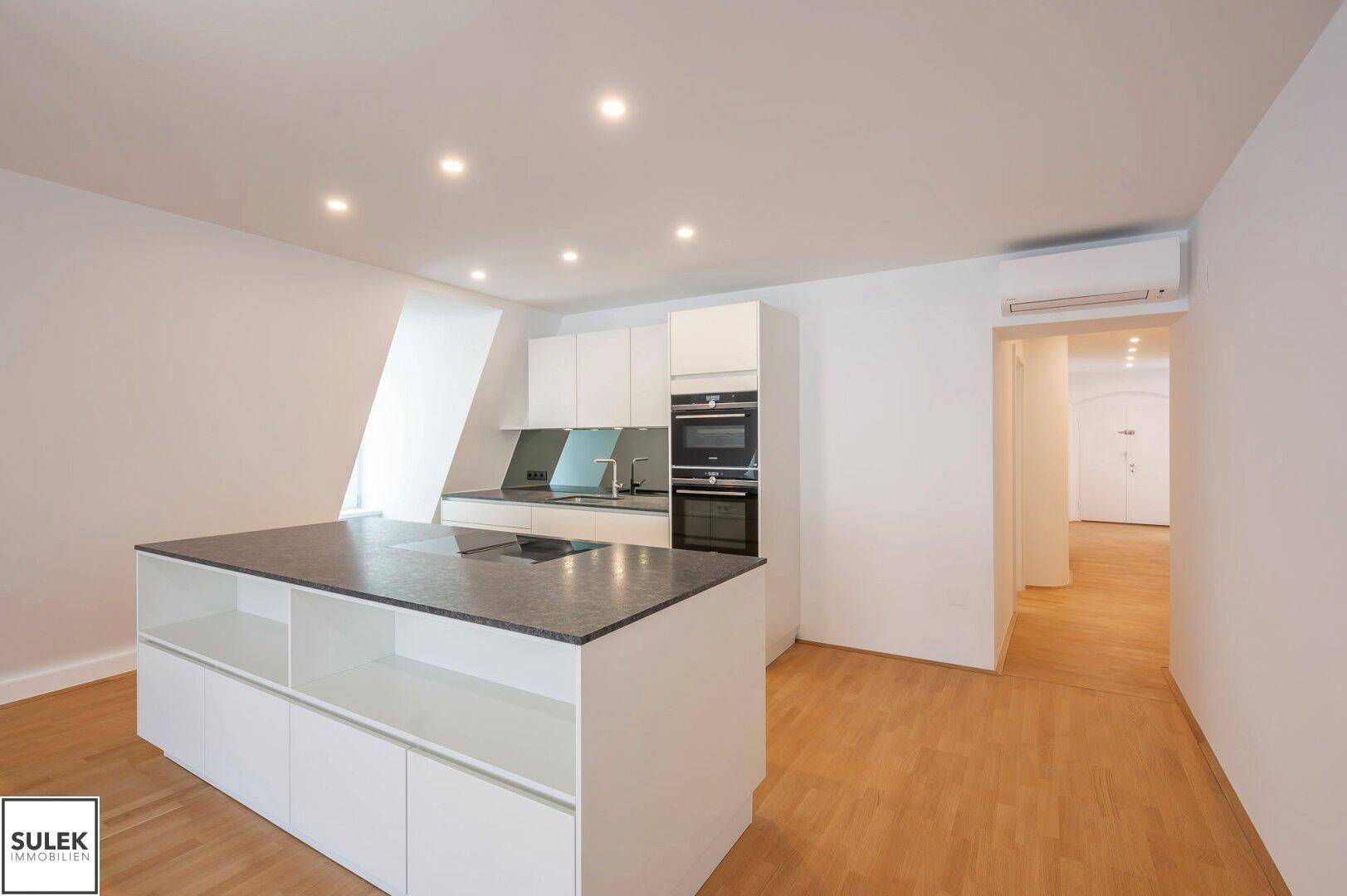 Moderne Einbauküche mit Kücheninsel, integrierten Geräten und hellem Parkettboden.