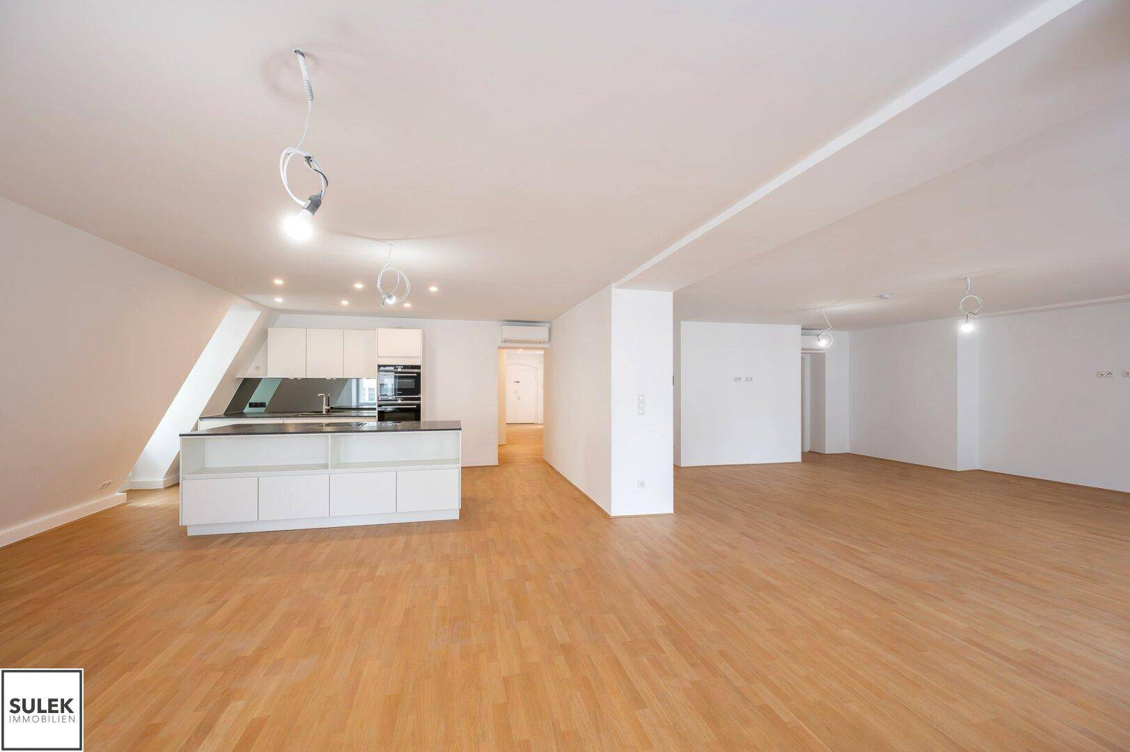 Offener Wohnbereich mit moderner Kücheninsel und Parkettboden, ideal für geselliges Beisammensein.