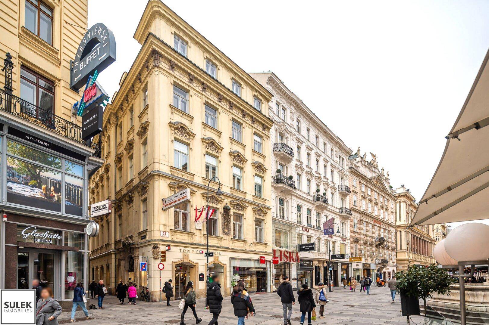 Belebtes Stadtbild mit historischen Gebäuden, Geschäften und vielen Passanten.