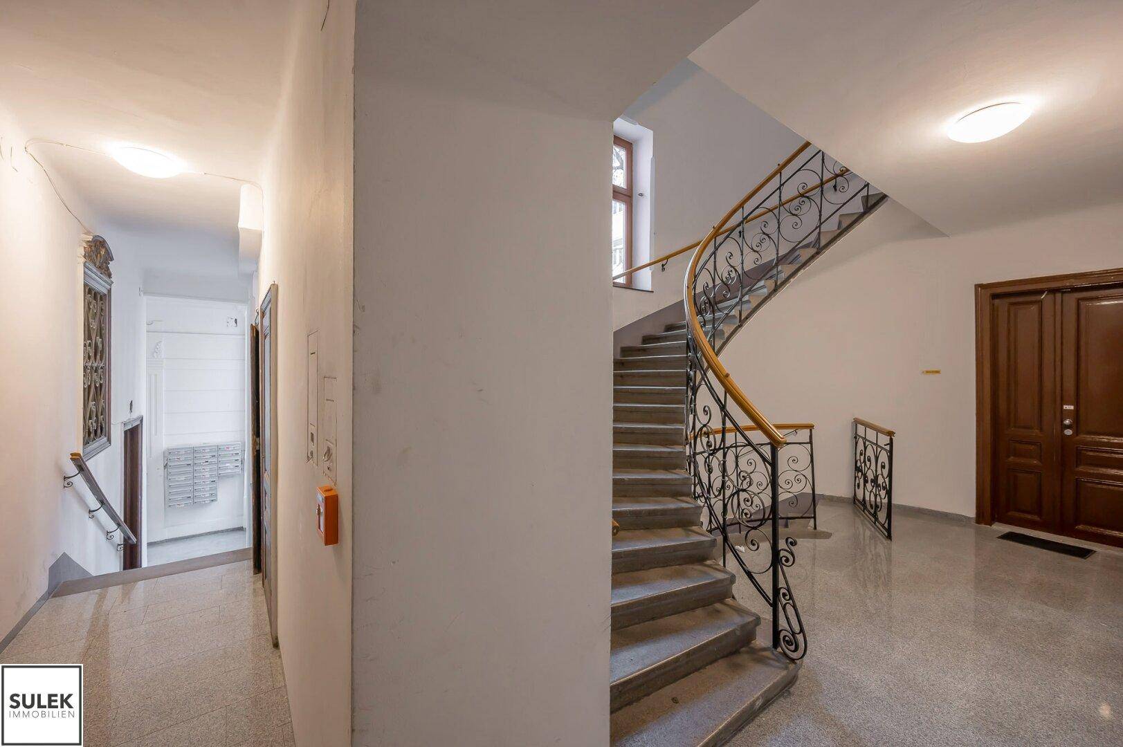Historisches Treppenhaus mit schmiedeeisernem Geländer und Terrazzoboden in einem Altbau.