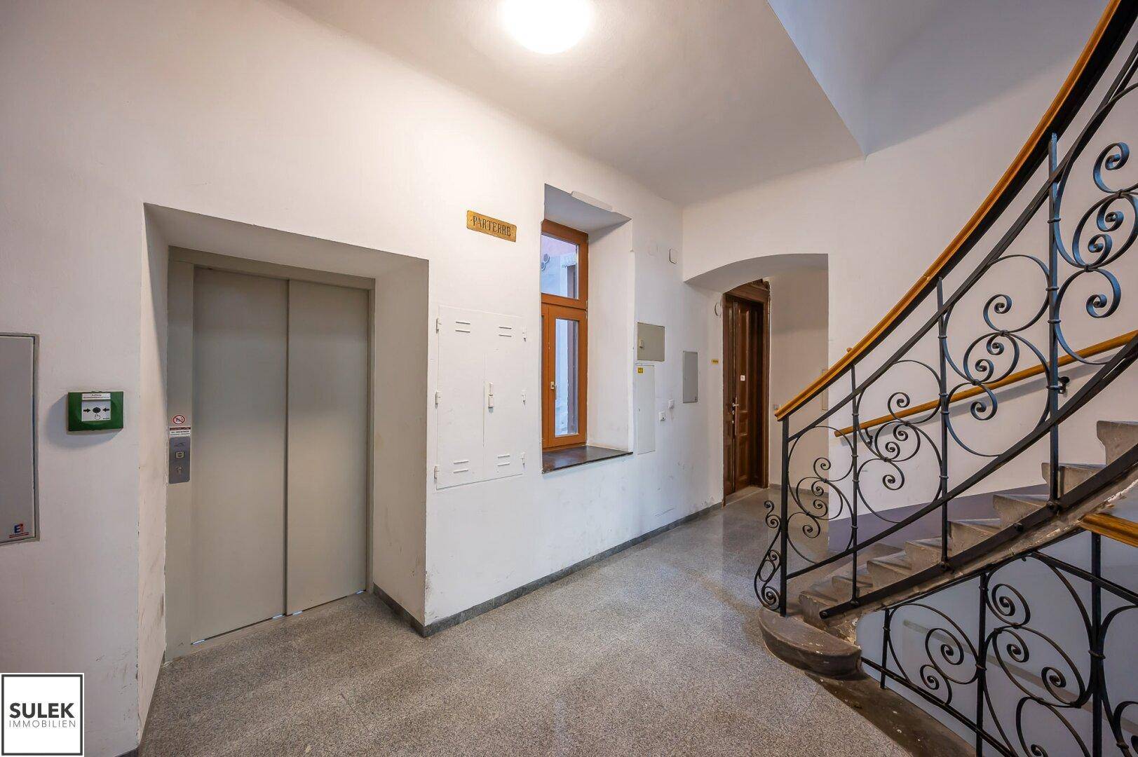 Heller Eingangsbereich mit Aufzug und Treppenaufgang in einem gepflegten Mehrfamilienhaus.