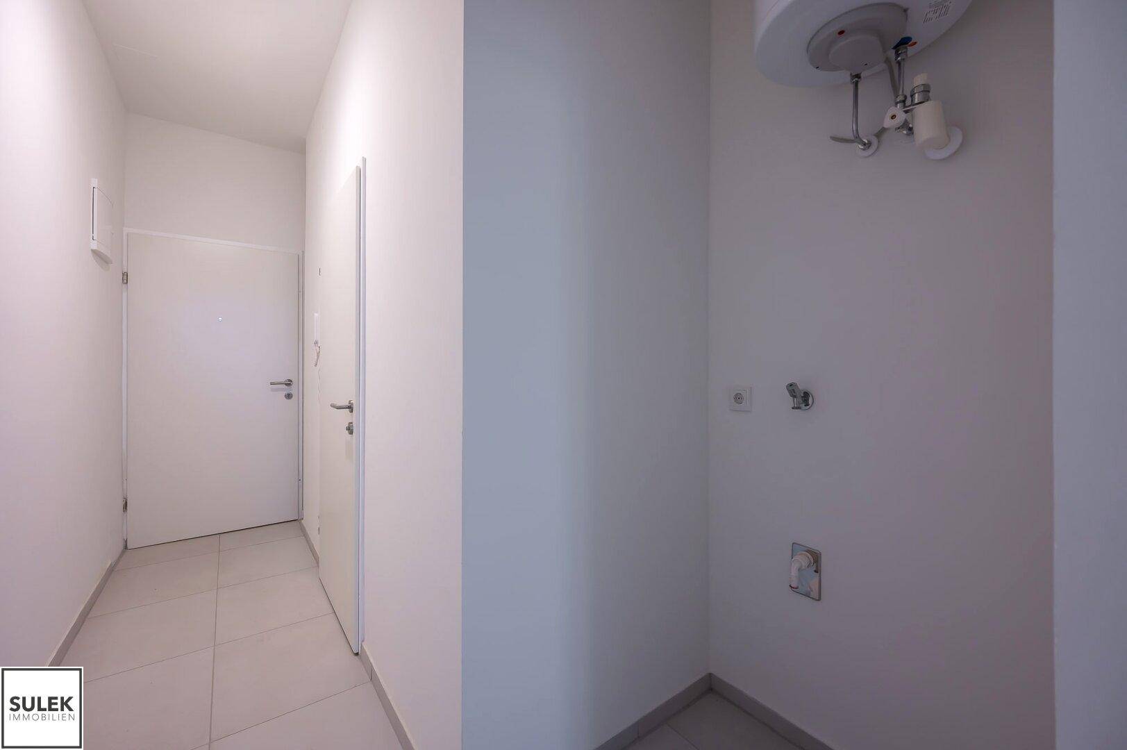 Kleiner Abstellraum mit Anschlüssen für Warmwasserbereiter und Waschmaschine.