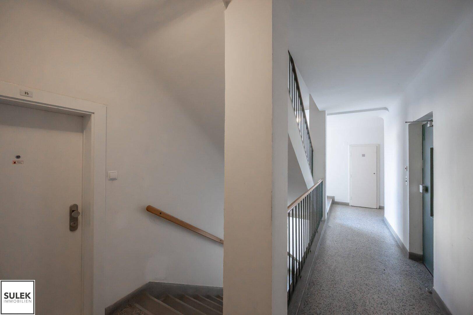 Treppenhaus und Flur in einem Mehrfamilienhaus mit Zugang zu den einzelnen Wohneinheiten.