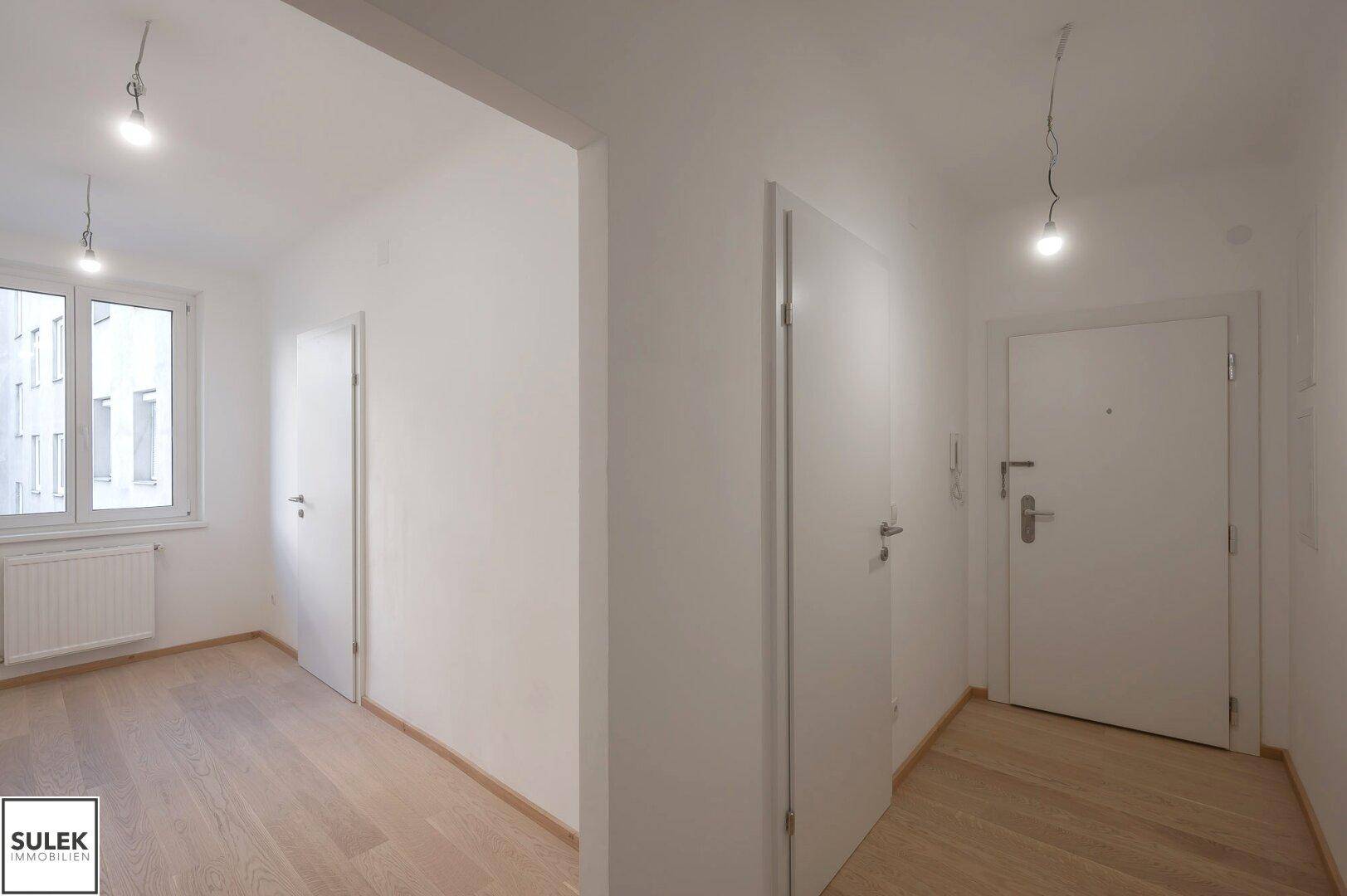 Heller Flur mit Holzboden, der zu weiteren Zimmern und dem Eingangsbereich der Wohnung führt.
