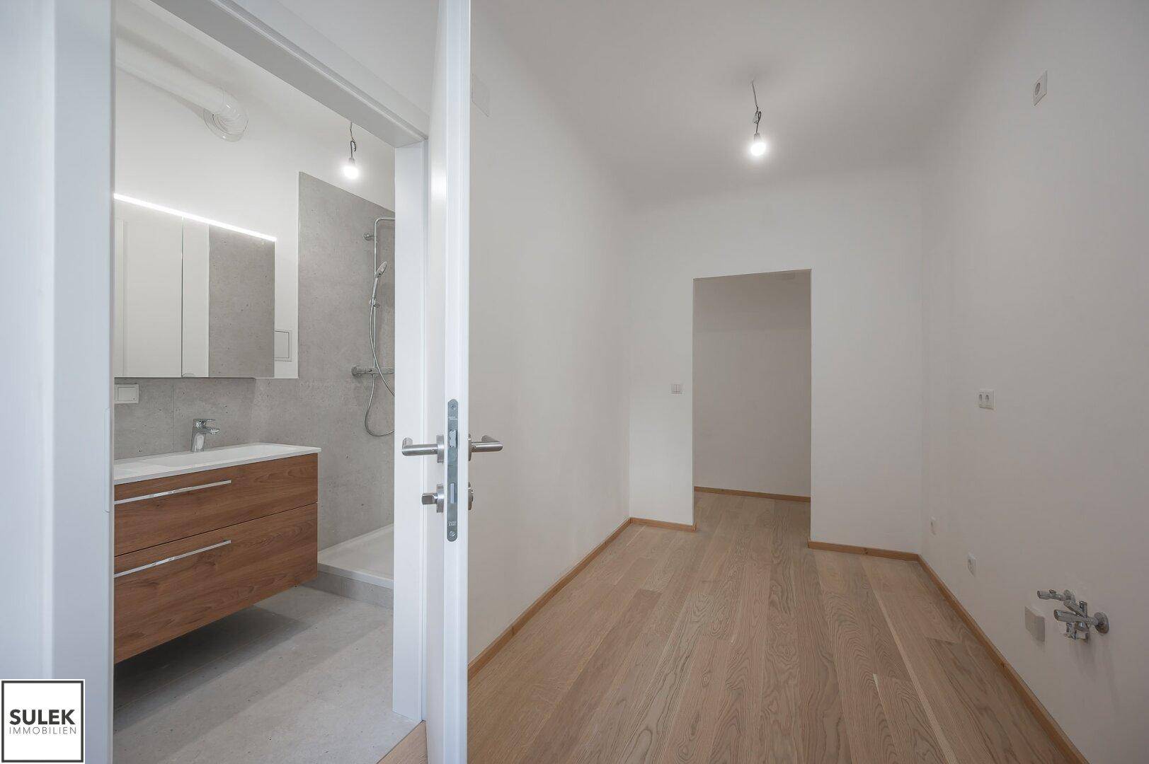 Helles Zimmer mit Holzboden und direktem Zugang zu einem modernen Badezimmer.