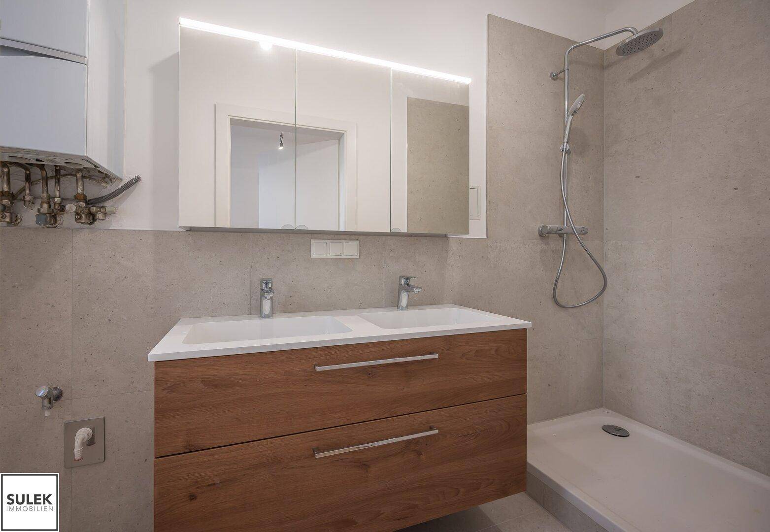 Modernes Badezimmer mit Doppelwaschbecken, Spiegelschrank und Duschbereich mit Regendusche.