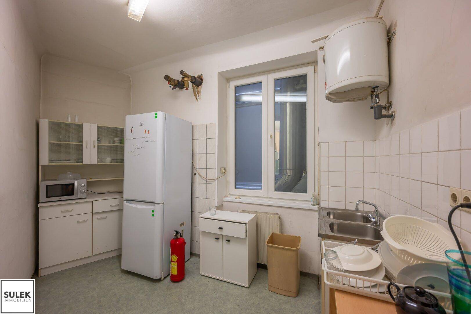 Funktionale Küche mit Kühlschrank, Mikrowelle und Spülbecken, ideal für die Mitarbeiterversorgung.
