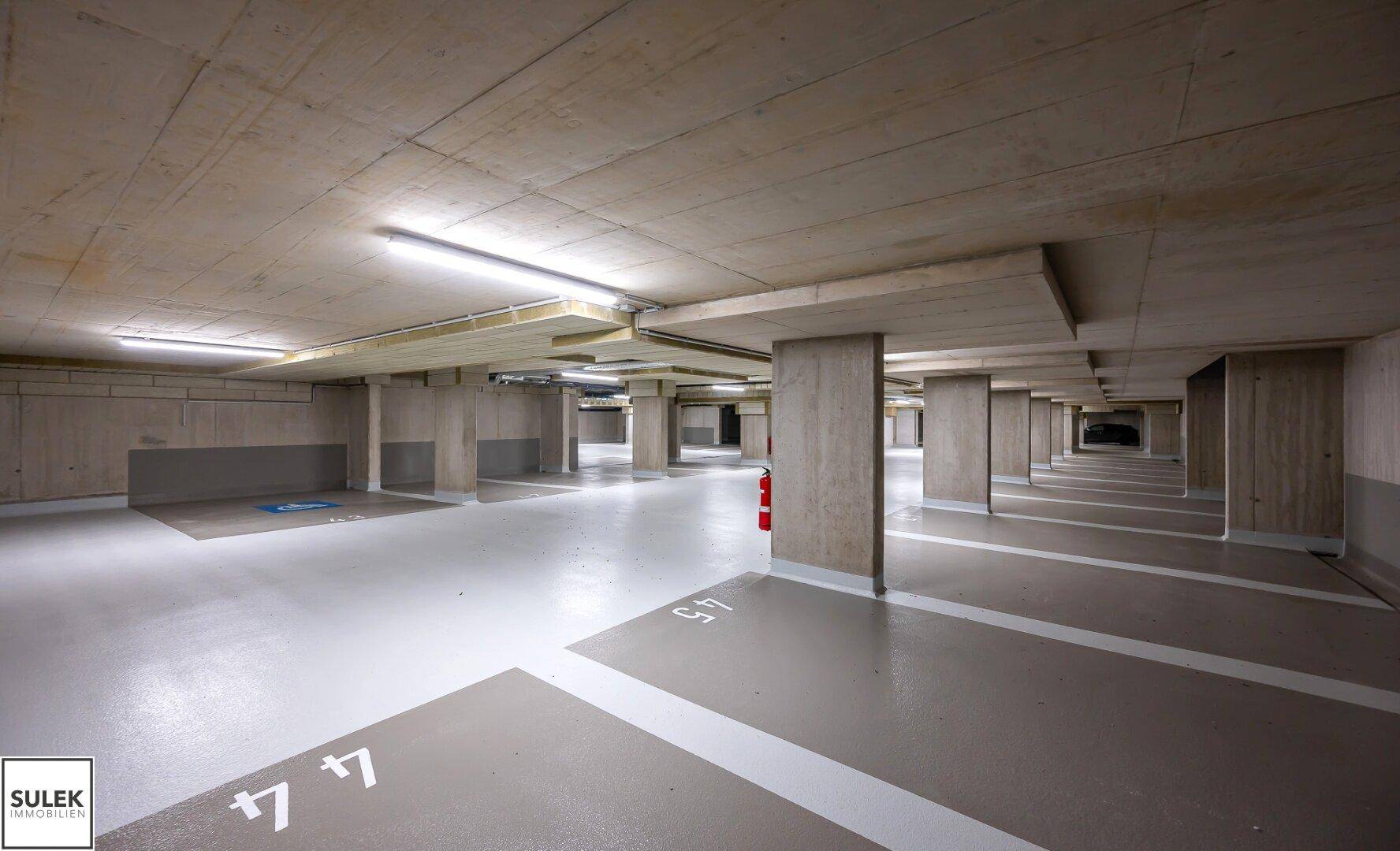 Geräumige Tiefgarage mit markierten Stellplätzen und Betonstützen.