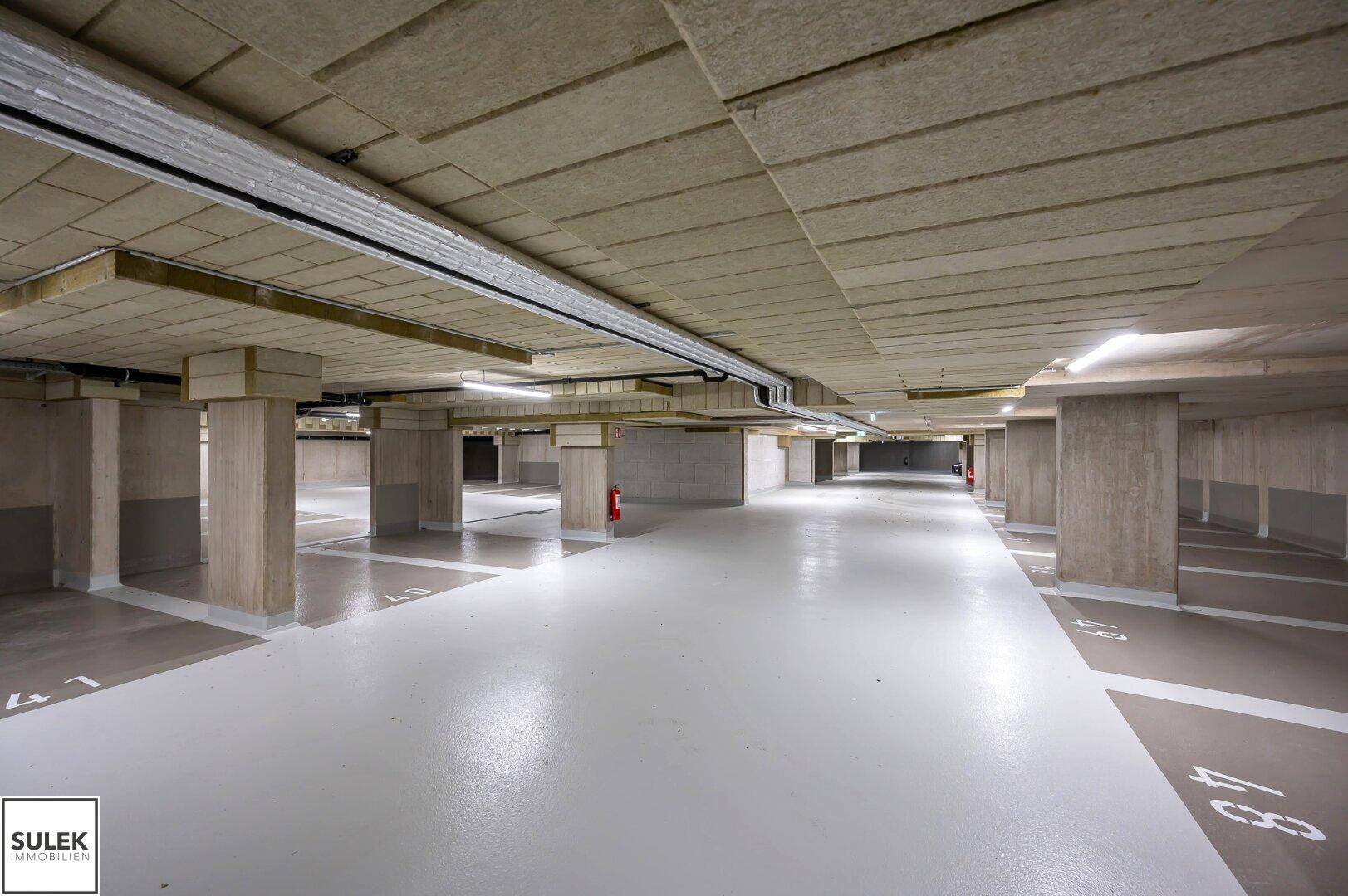 Geräumige Tiefgarage mit markierten Stellplätzen und Betonstützen.