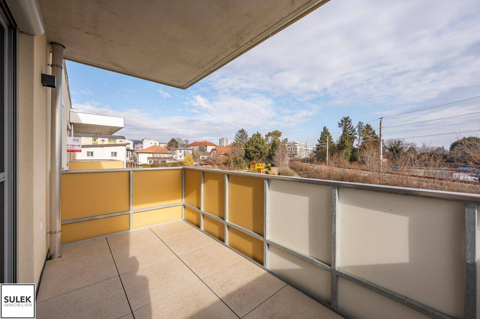 Geräumiger Balkon mit Fliesenboden und Blick auf die Umgebung, ideal zum Entspannen.