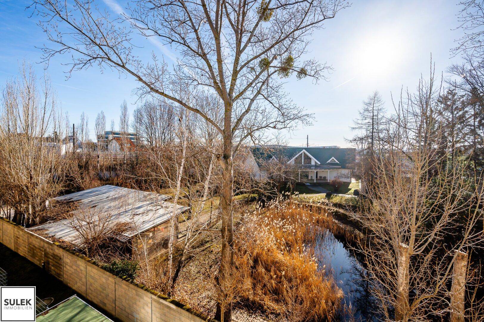 Weitläufiger Blick vom Balkon auf einen Teich und die grüne Umgebung.