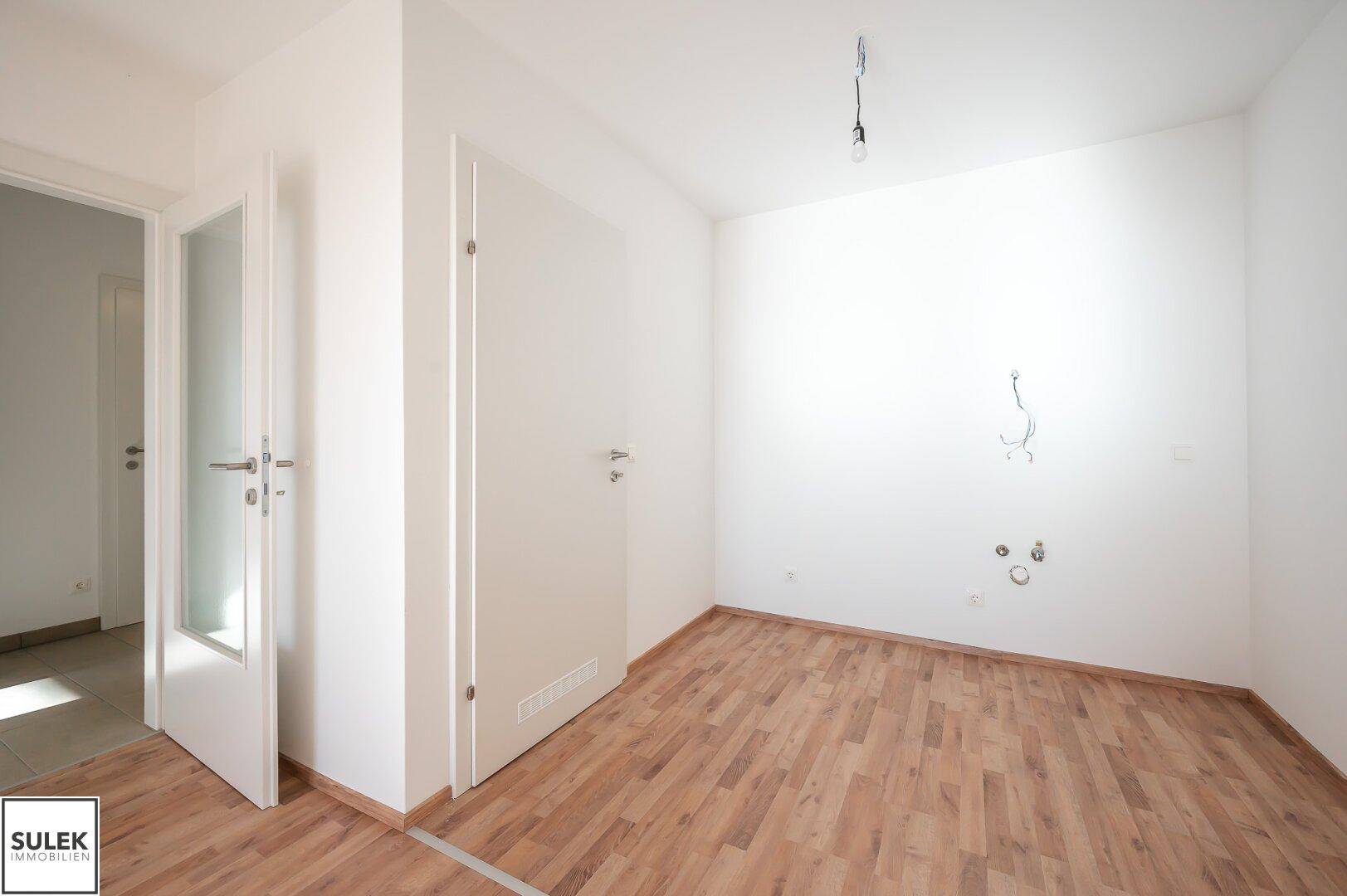 Heller Bereich im Wohnzimmer mit Anschlüssen für eine zukünftige Küche.