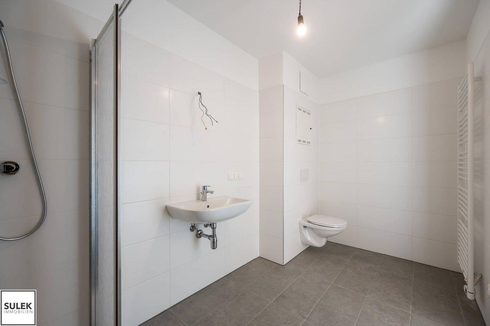 Modernes Badezimmer mit Dusche, Waschbecken und wandhängendem WC.