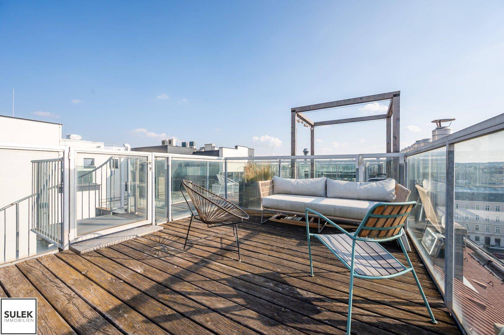 Moderne Dachterrasse mit Lounge-Möbeln und Glasgeländer.