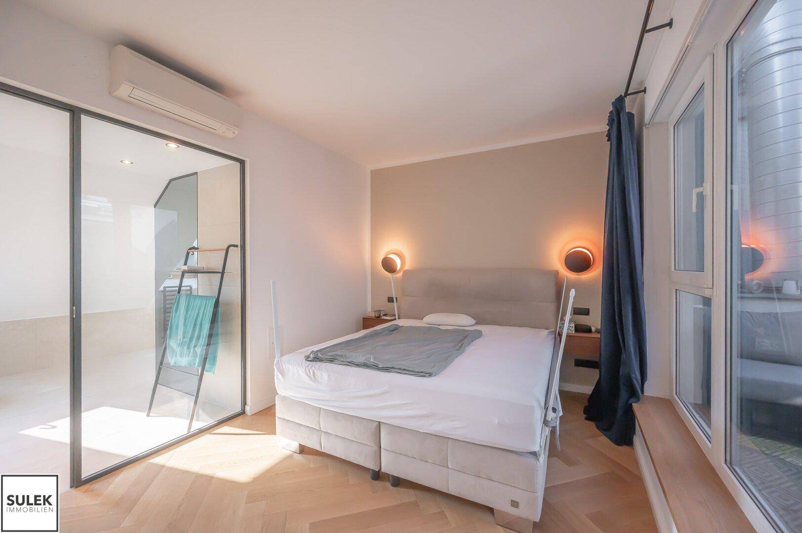 Gemütliches Schlafzimmer mit Doppelbett, Klimaanlage und großen Fenstern.