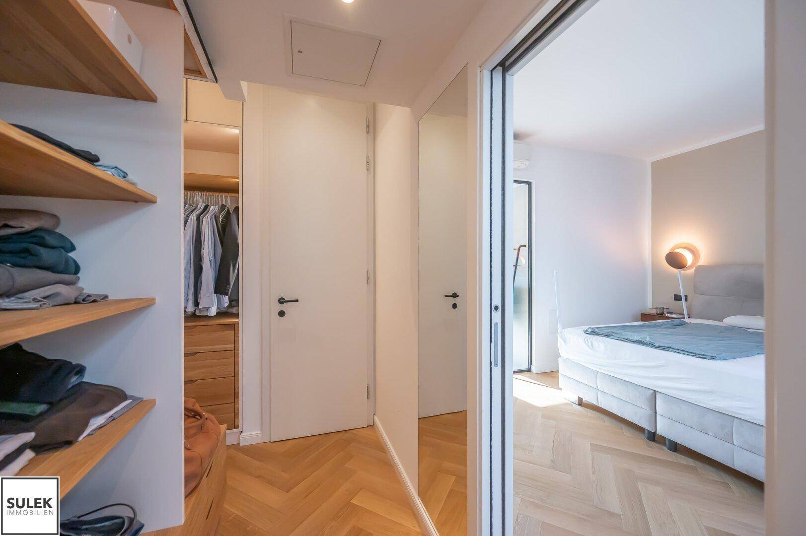 Begehbarer Kleiderschrank mit Holzregalen und direktem Zugang zum Schlafzimmer.