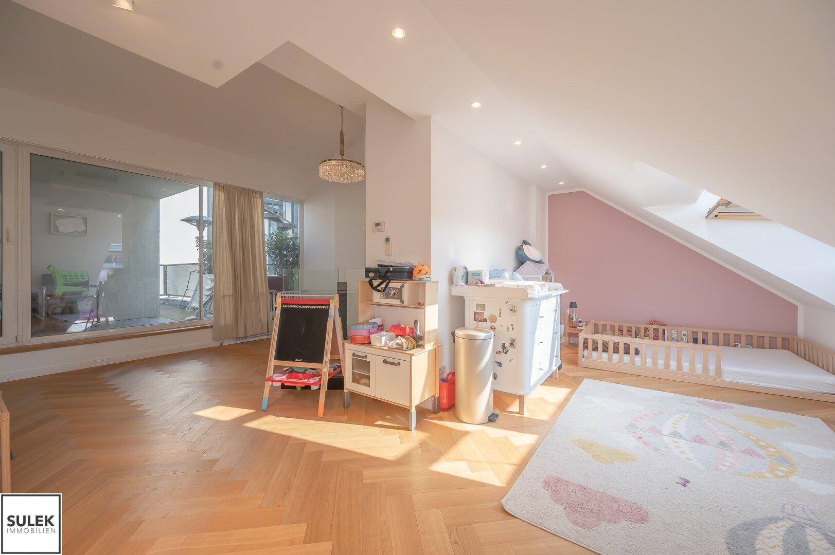 Helles Kinderzimmer im Dachgeschoss mit Spielbereich und Zugang zur Terrasse.