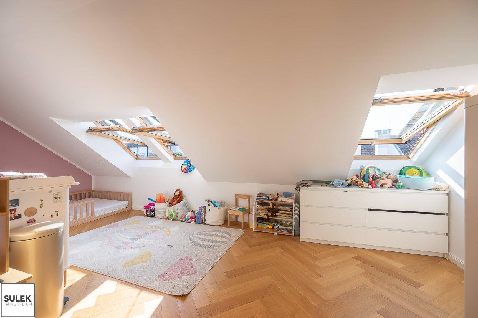 Lichtdurchflutetes Kinderzimmer mit mehreren Dachfenstern und Spielzeug.