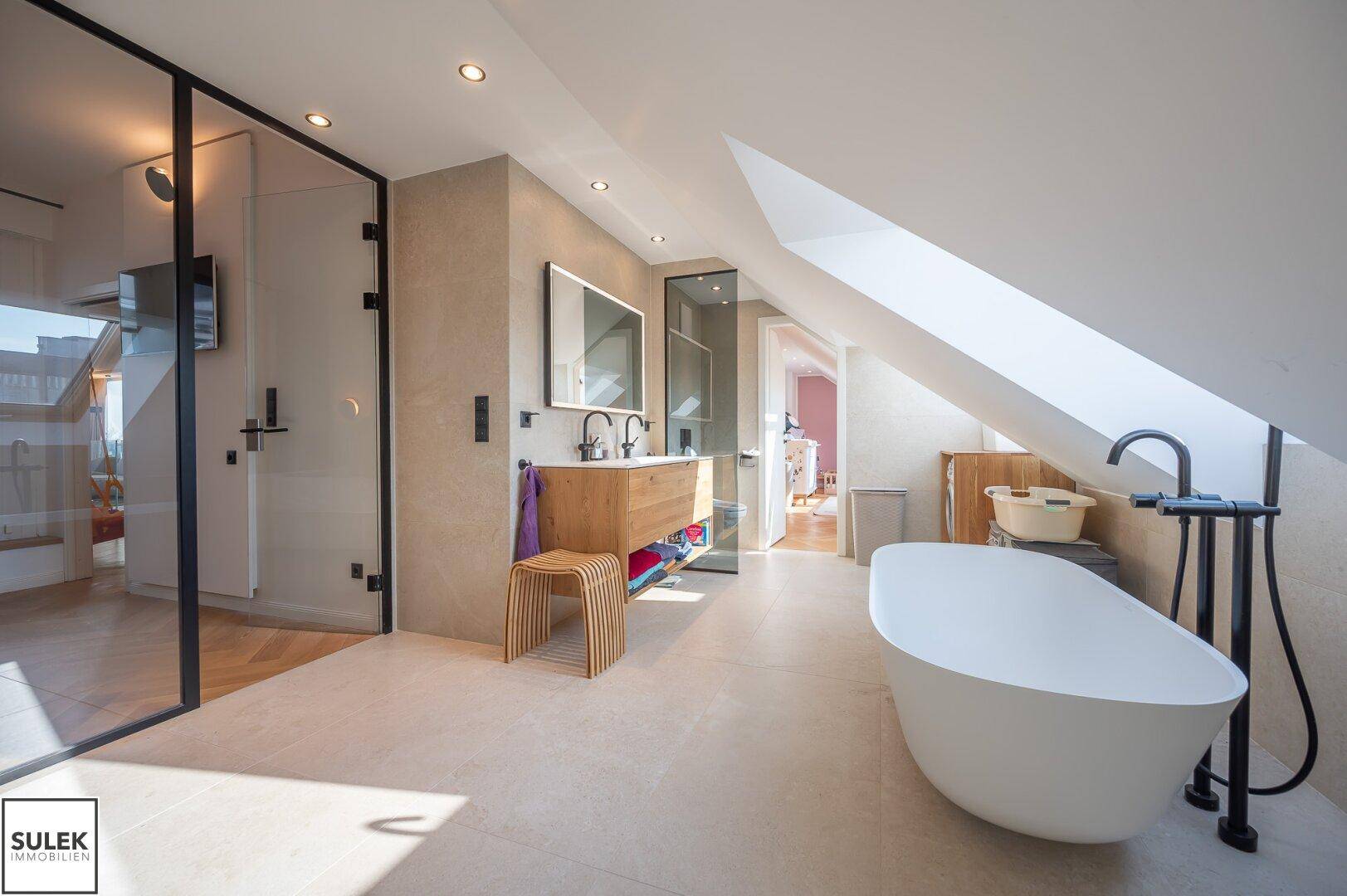Geräumiges Badezimmer mit freistehender Wanne, Glasdusche und Holzwaschtisch.