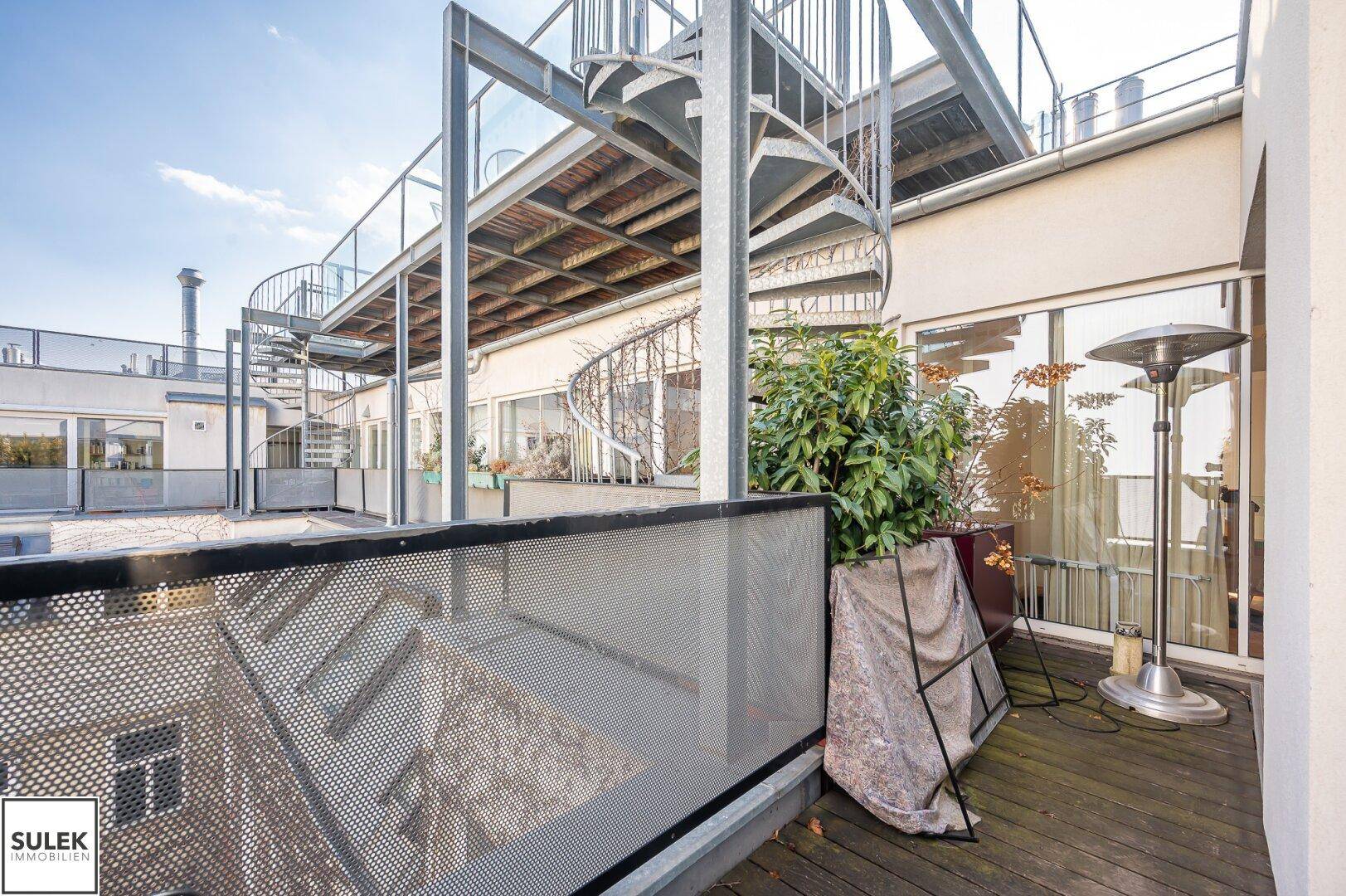Geräumige Terrasse mit Metallgeländer und Wendeltreppe zum oberen Bereich.